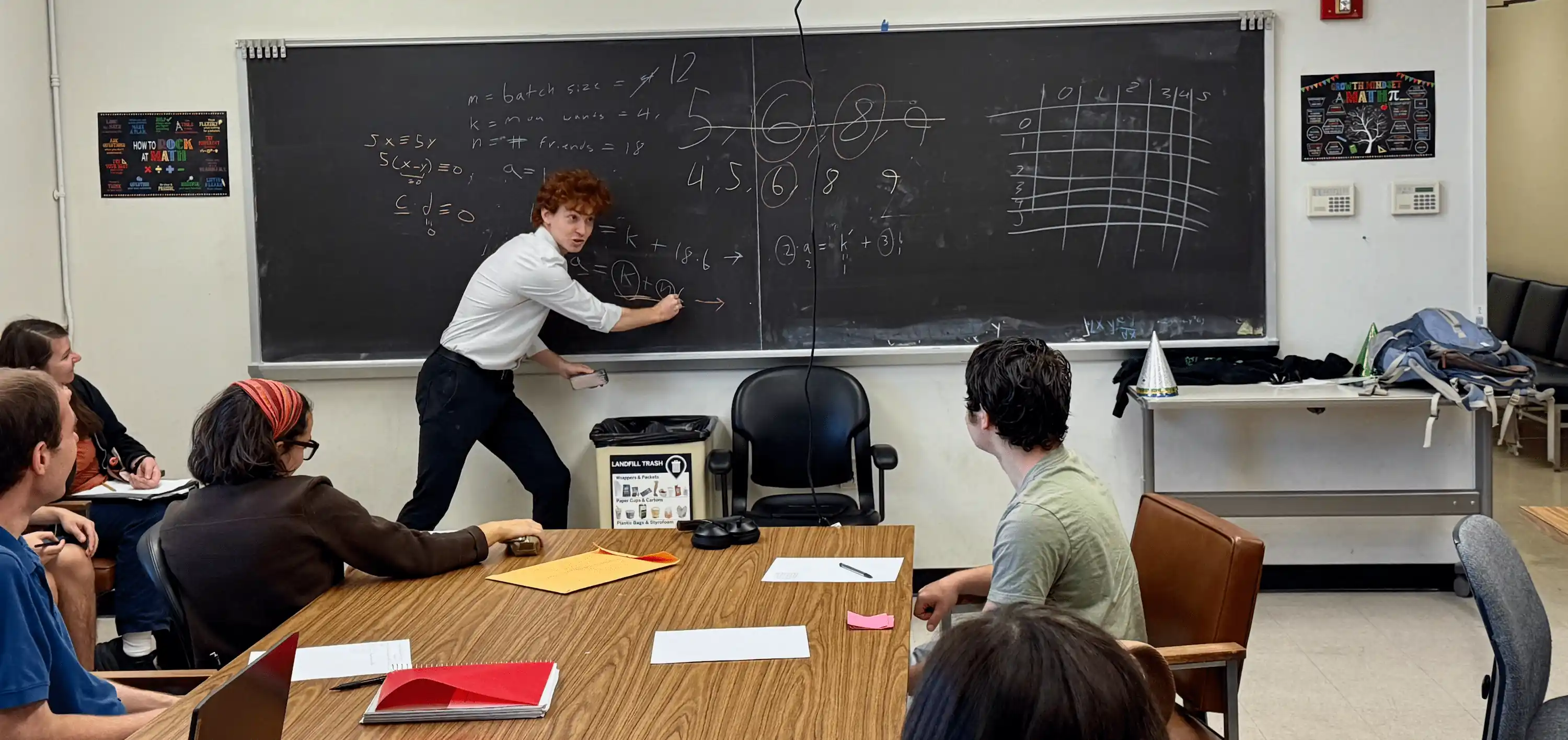 Dillon Grannis tutoring students at a blackboard